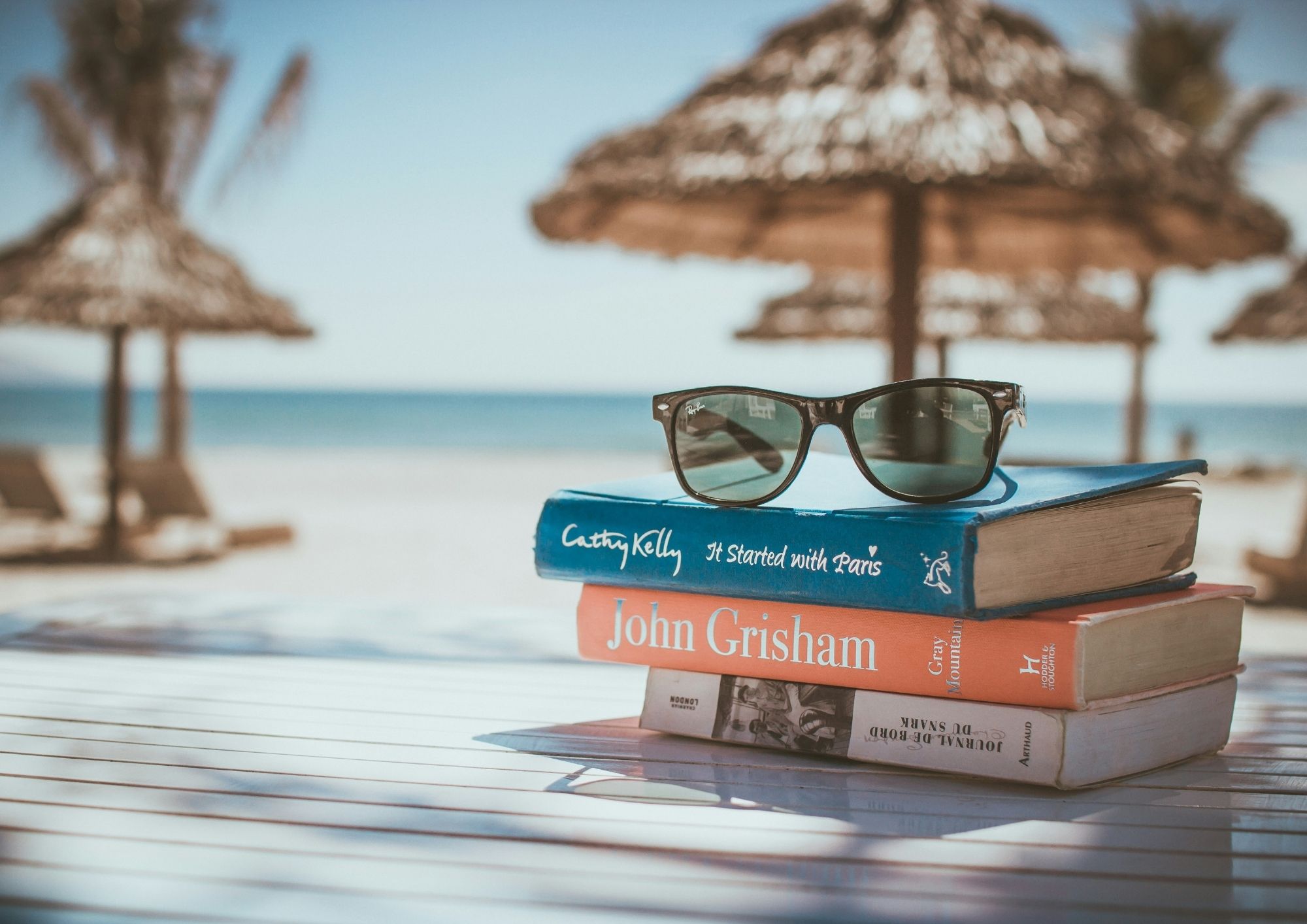 Relaxing beach scene with books and sunglasses, perfect for a UK holiday.