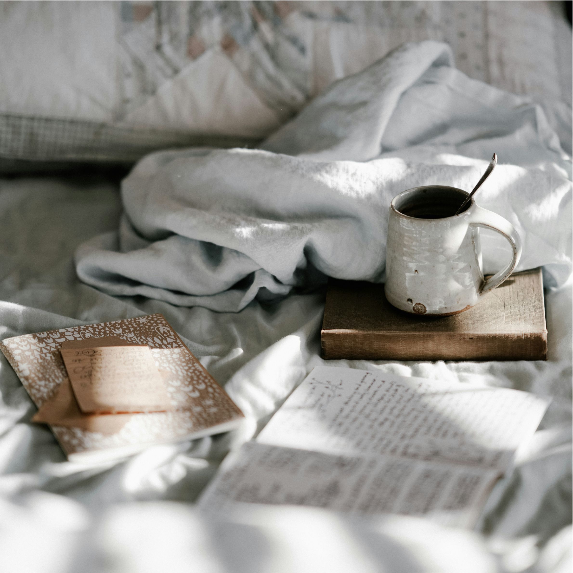 A cozy scene on a bed with a journal and a mug of tea—capturing the calm reminder that rest is productive.
